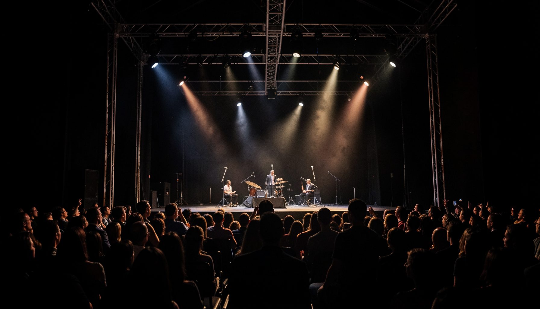 A formal event setting with stage lighting, microphones, and an audience, captured in a documentary style with deep blacks and warm highlights.