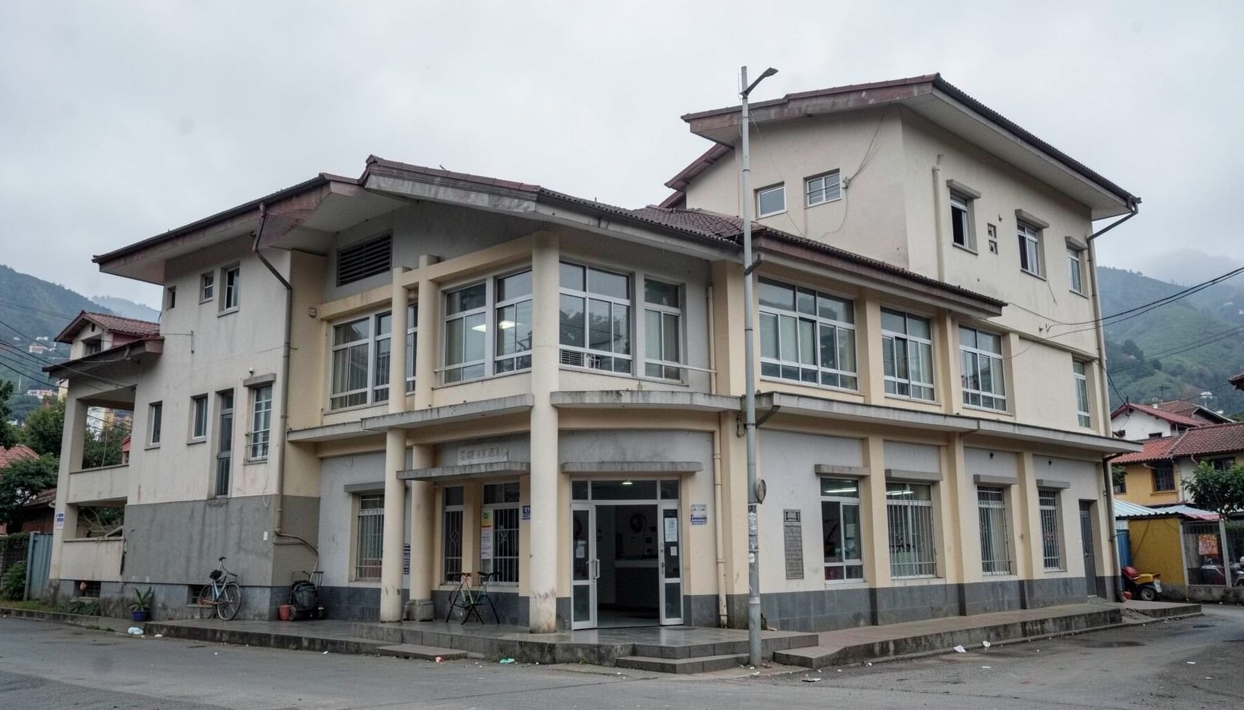An exterior view of a police station building in Kathmandu, muted grey and beige tones, overcast sky, calm and factual atmosphere.
