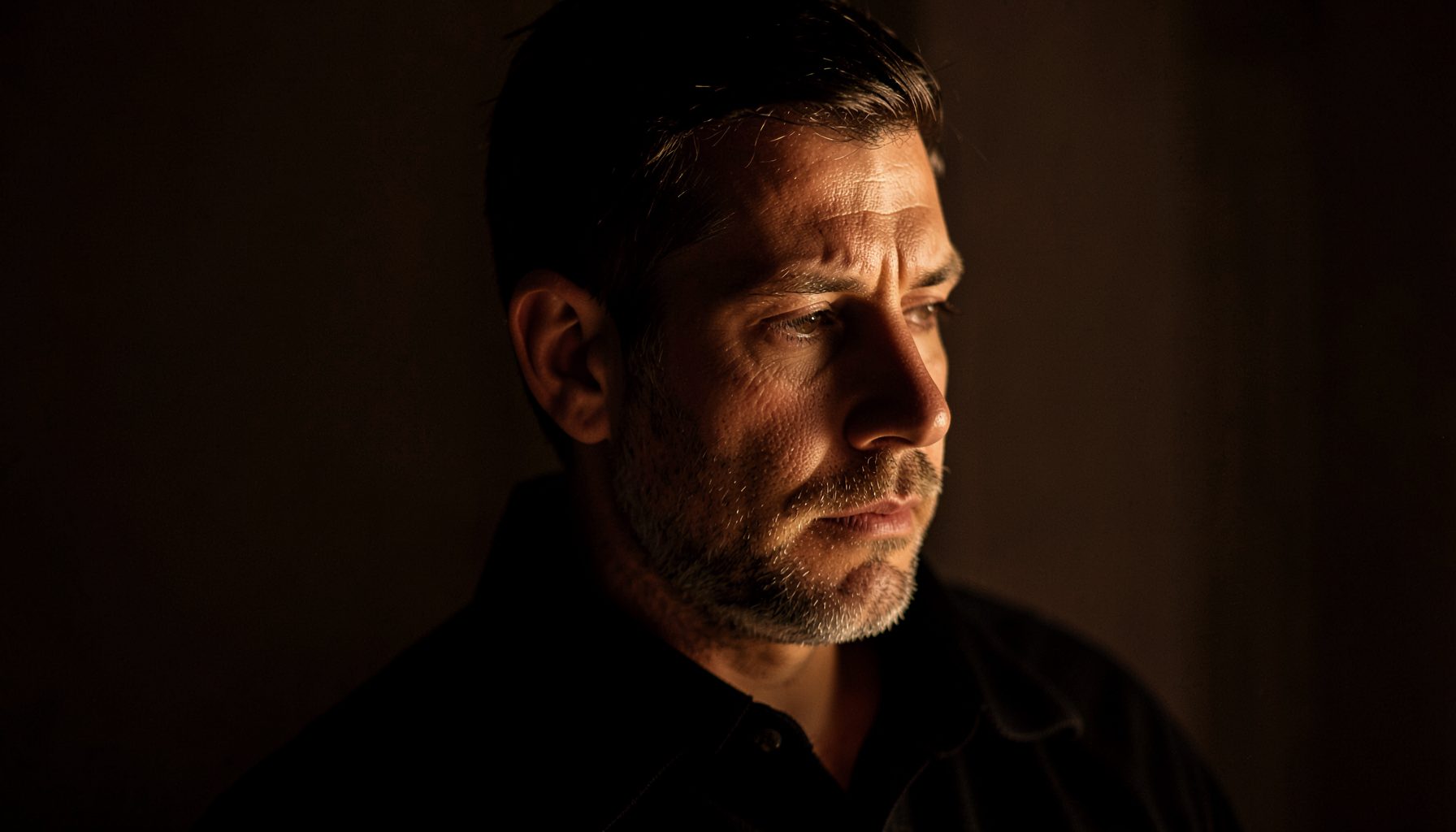 Dramatic side-lit portrait in deep brown and ivory tones, contemplative mood